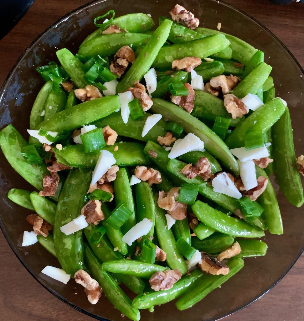 snap peas in a bowl with walnuts and truffle bag goat cheese