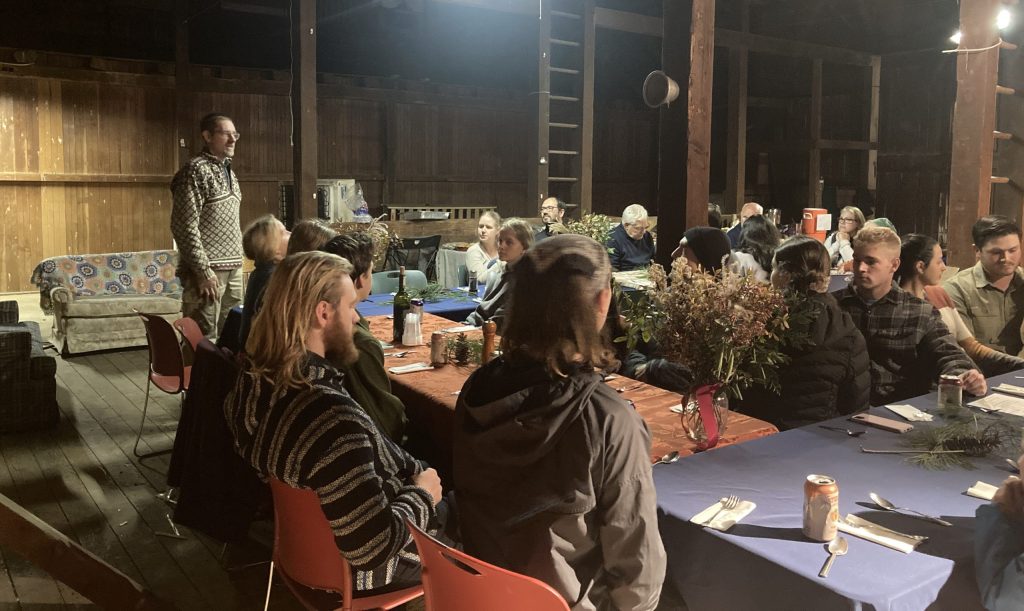 Farmer Reuben addressing the friends and family of the organic farm in the barn before the feast